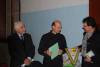 il Segretario del Coro La Pineta consegna il Gagliardetto del Coro a Don Massimo. Sulla sinistra il Generale degli Alpini, Dott. Chichi